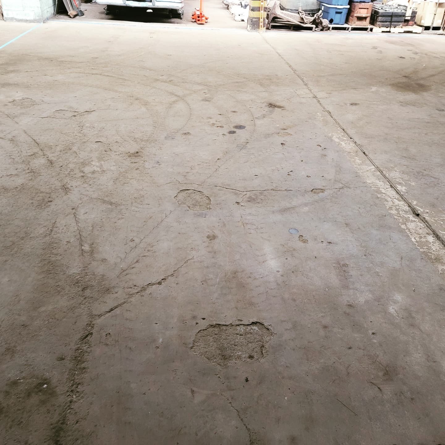 Worn concrete floor with spalling and staining before coating